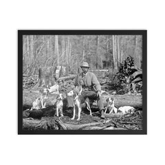 A deer hunter poses for a portrait with his hounds, 1897 framed print on a plain backdrop in size 16"x20".