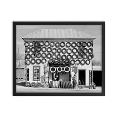 Firestone Tire Shop, 1940 - a used tire shop and filling station displaying tires from top to bottom San Marcos, Texas framed print on a plain backdrop in size 16"x20".