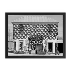 Firestone Tire Shop, 1940 - a used tire shop and filling station displaying tires from top to bottom San Marcos, Texas framed print on a plain backdrop in size 18"x24".