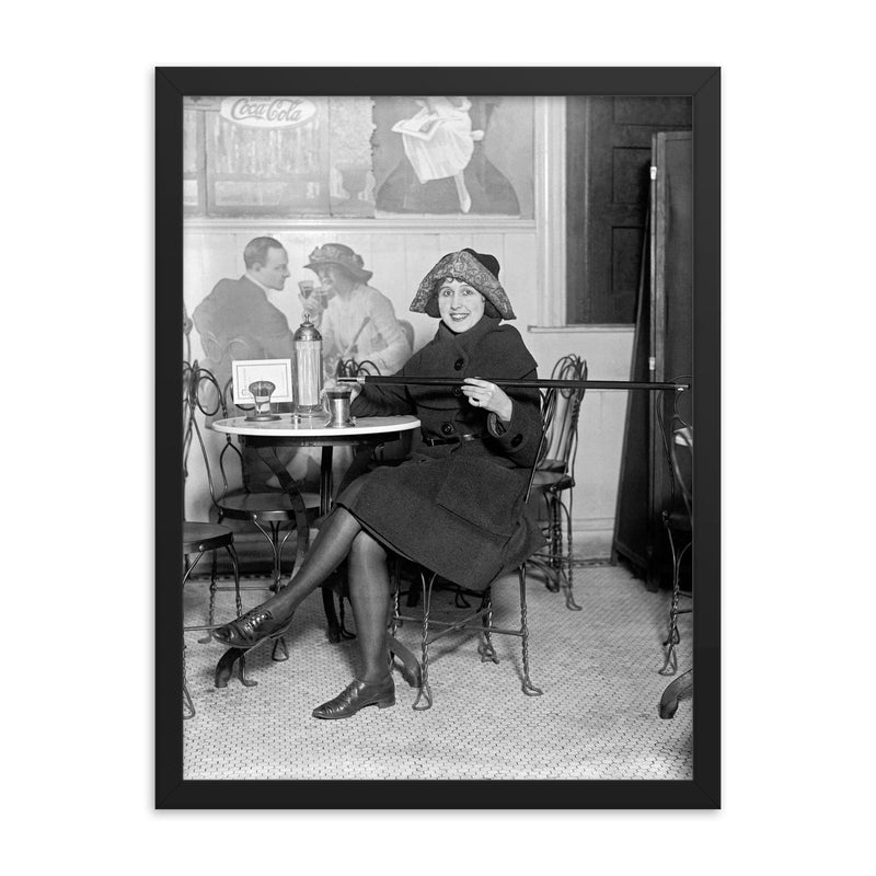Lady with a hidden flask - a woman pours a drink from a flask hidden inside a cane during the Prohibition era, 1922 framed print on a plain backdrop in size 18