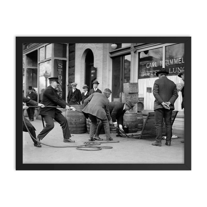 Police seizing bootleg liquor - Police haul barrels of illegal liquor from the basement of a speakeasy during the era of alcohol prohibition, 1923 framed print on a plain backdrop in size 18