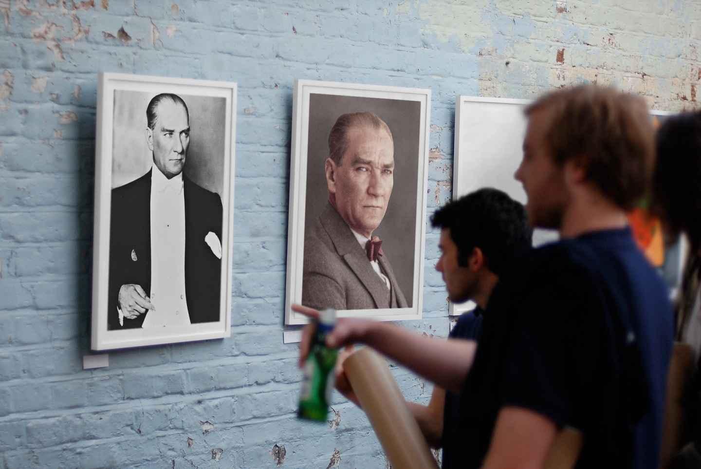 Mustafa Kemal Ataturk print displayed in an art gallery with people talking about it.