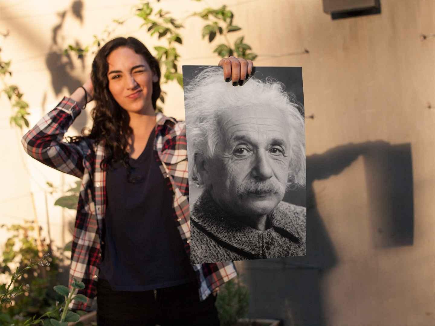 Young woman winking and holding up an Einstein poster.