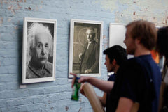 Einstein poster displayed in an art gallery with people talking about it.