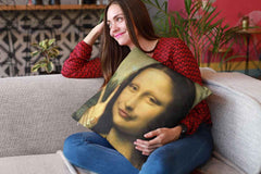 A young woman on a sofa holding a Mona Lisa meme pillow  and trying not to laugh.