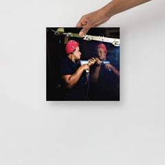 A Rosie the Riveter poster on a plain backdrop in size 12x12”.