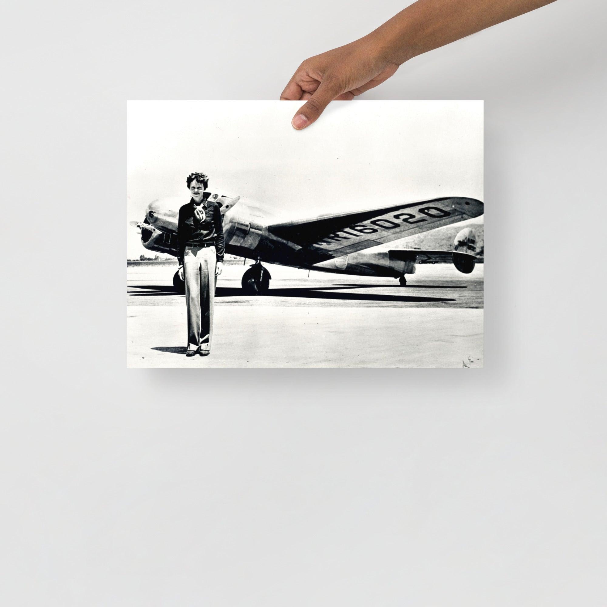 An Amelia Earhart standing in front of the Lockheed Electra on a plain backdrop in size 12x16”.
