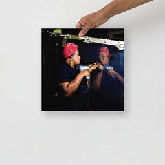 A Rosie the Riveter poster on a plain backdrop in size 14x14”.
