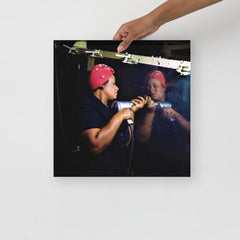 A Rosie the Riveter poster on a plain backdrop in size 16x16”.