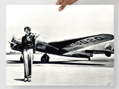 An Amelia Earhart standing in front of the Lockheed Electra on a plain backdrop in size 18x24”.